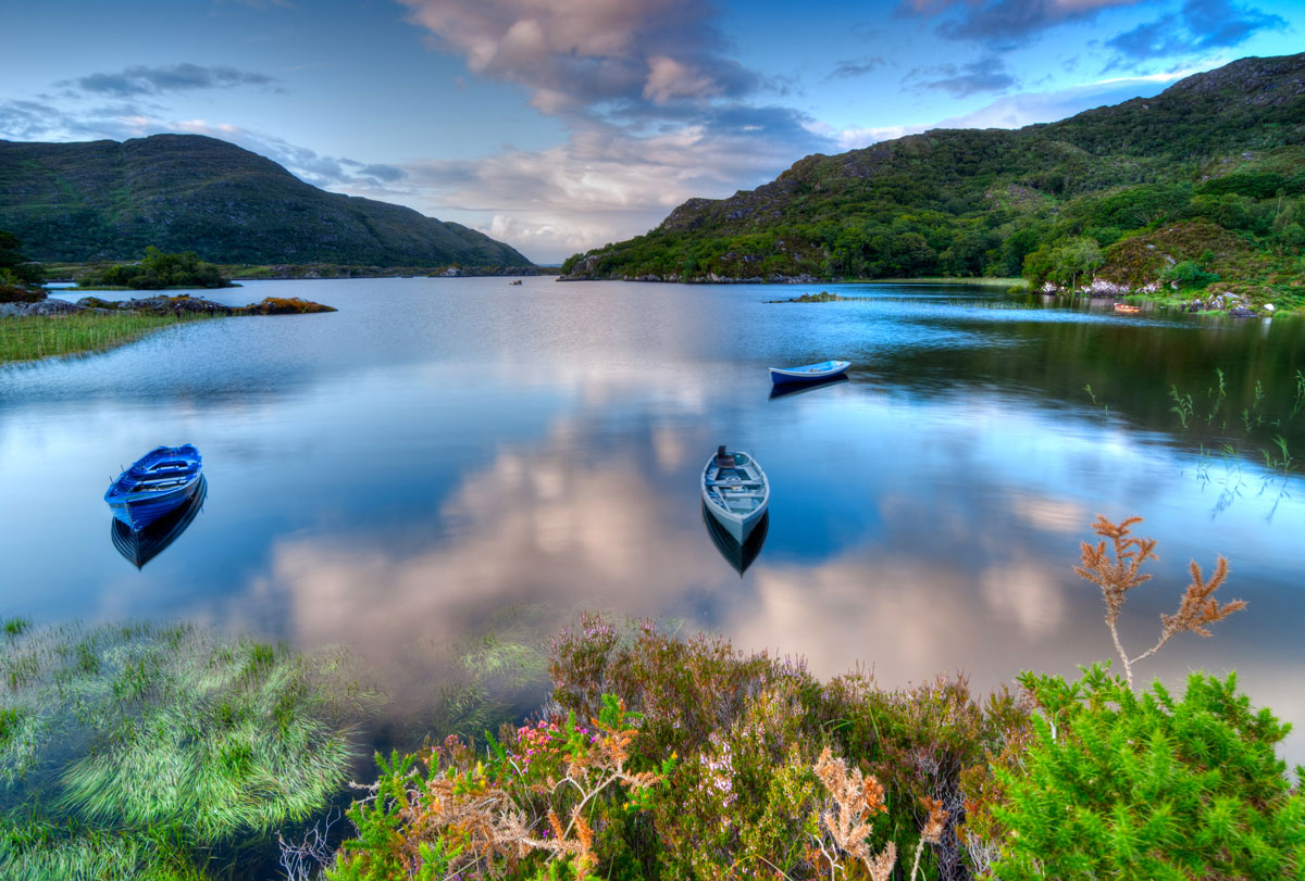 Rowing boats on a still lake among green mountains in Killarney National Park, Ireland