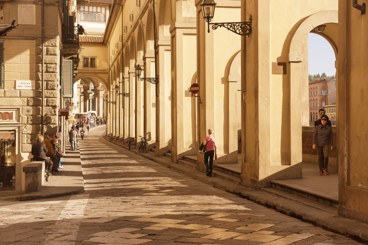 Sunlit stone arcade beside the Arno near the Uffizi in Florence's historic centre