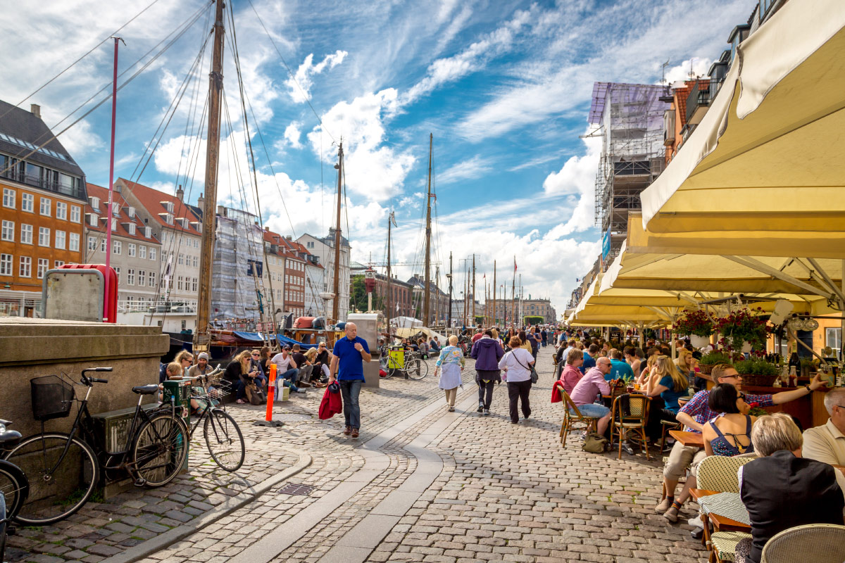 Outdoor cafes and tall ships along the colourful Nyhavn canal in Copenhagen, Denmark