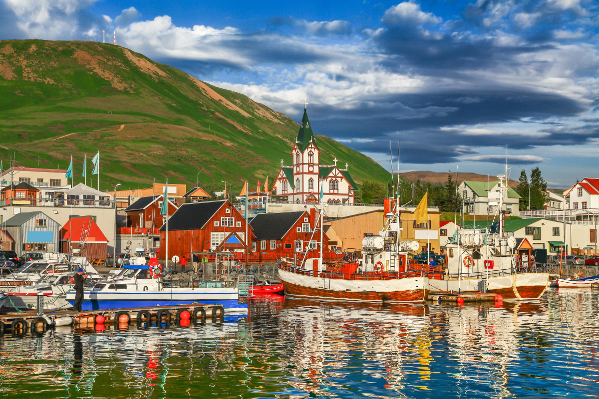 Colourful houses, wooden church and fishing boats in Húsavík harbour, Iceland