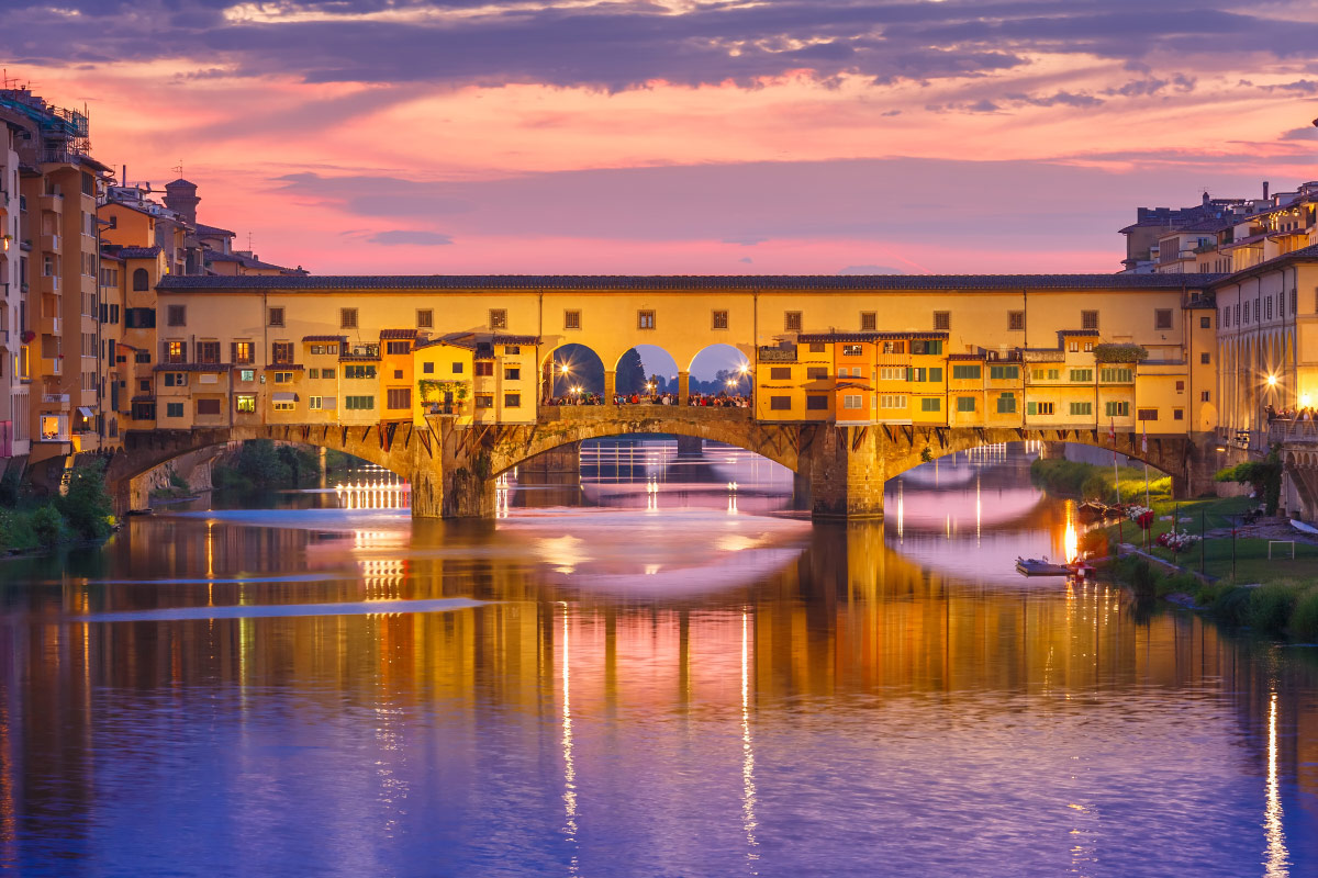 Ponte Vecchio lit up and reflected in the Arno River at dusk in Florence, Italy