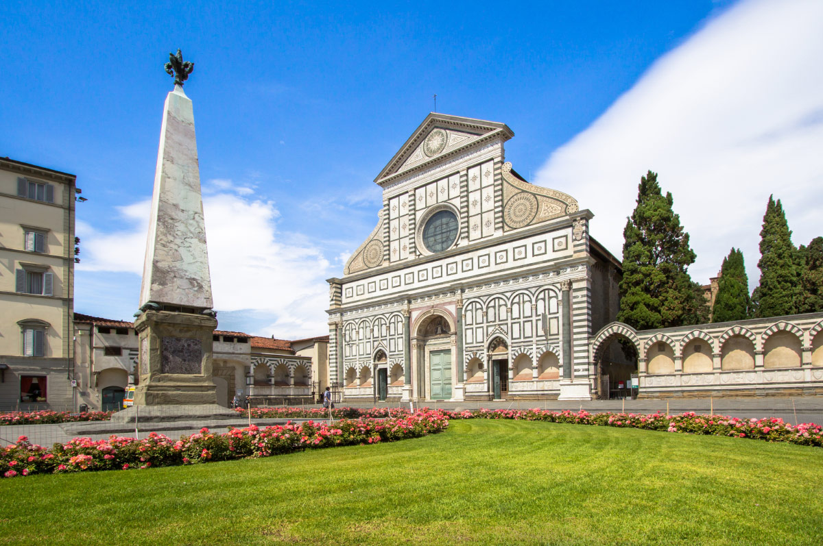 Marble facade of Santa Maria Novella church behind its lawn and obelisk in Florence