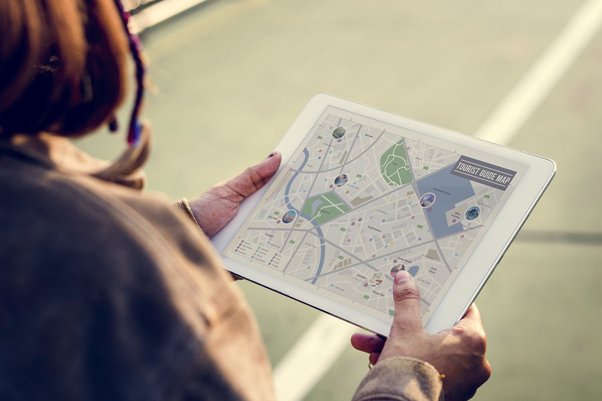 Hands holding a tablet showing a city tourist map outdoors
