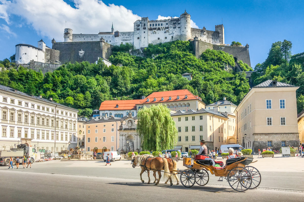 The historic city of Salzburg with traditonal horse-drawn Fiaker carriage and famous Hohensalzburg Fortress, places to visit in Austria
