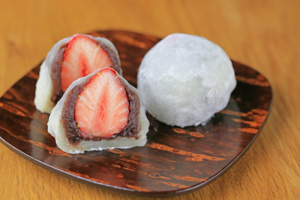 Strawberry daifuku cut open to show red bean paste and fresh strawberry