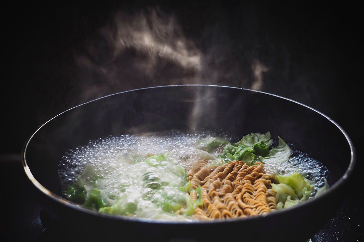 Buckwheat noodles and cabbage boiling in a steaming pan for vegetable ramen
