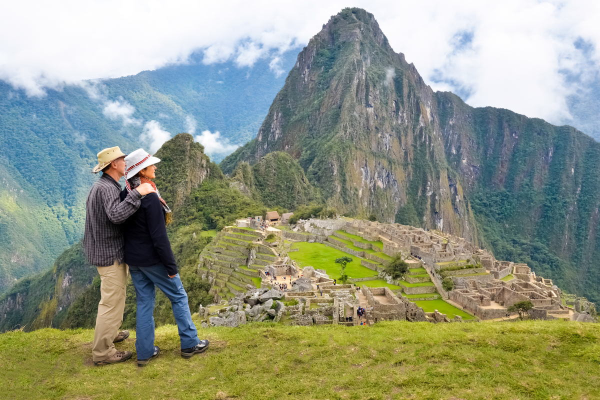 Older couple embracing on a hillside above Machu Picchu and Huayna Picchu, Peru