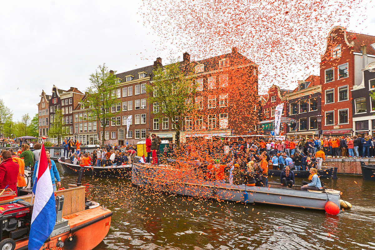 Boats and confetti on canals in Amsterdam King's Day