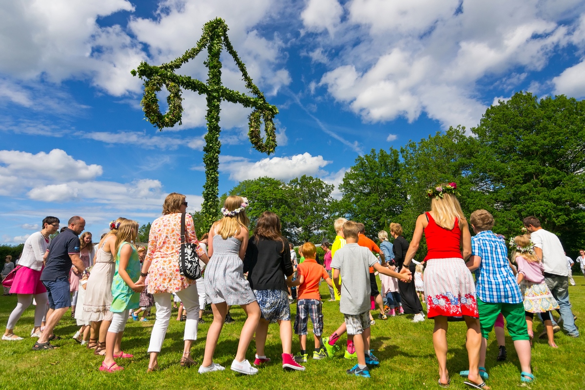 People celebrate midsummer around maypole in Sweden Summer Solstice