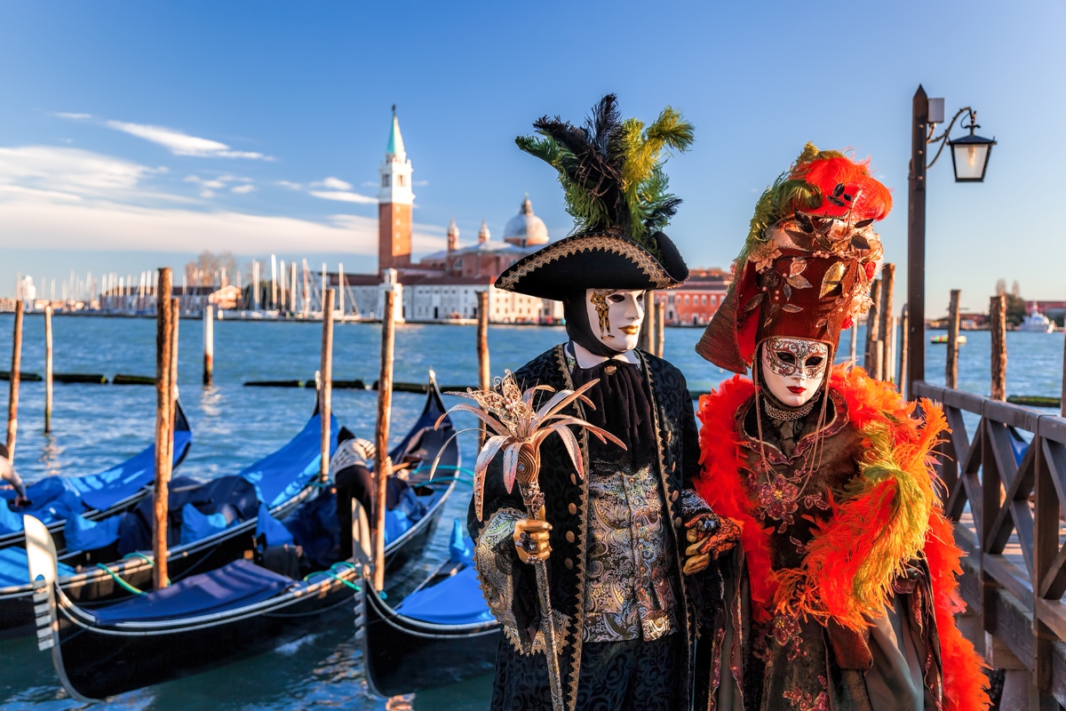 Two people dressed up in masks and traditional garb at one of the top Italian festivals