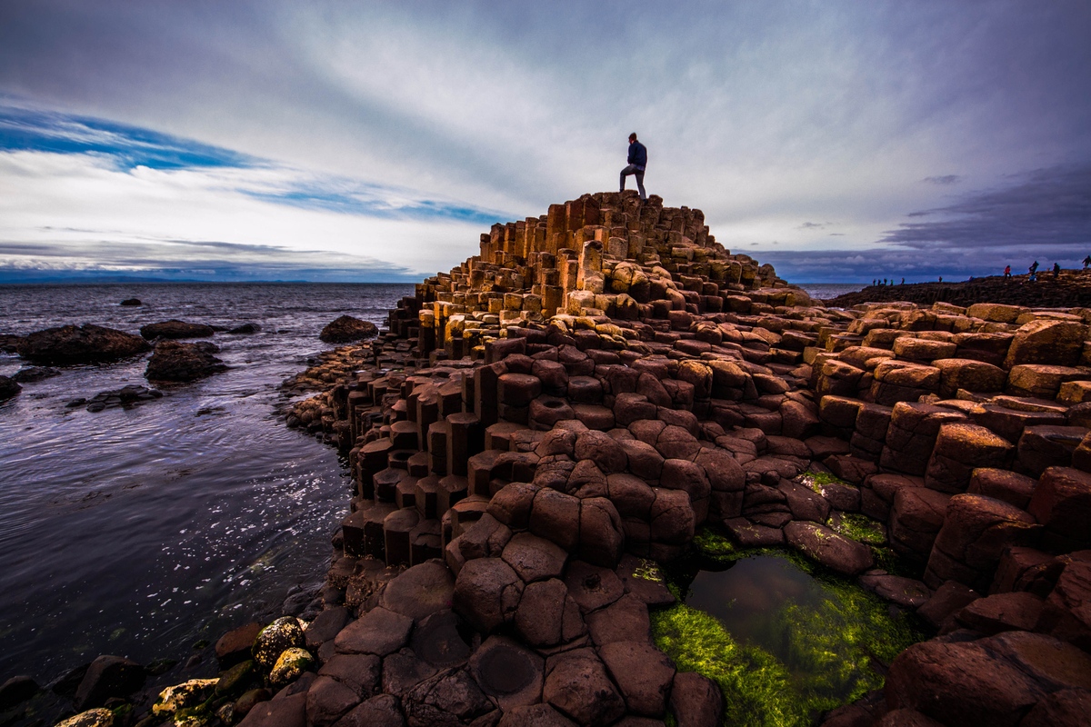 Man standing on basalt columns at the Giant's Causeway, Northern Ireland, World Heritage Site